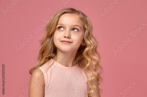 Little Girl With A Blond Curly Hair In A Pink Dress Is