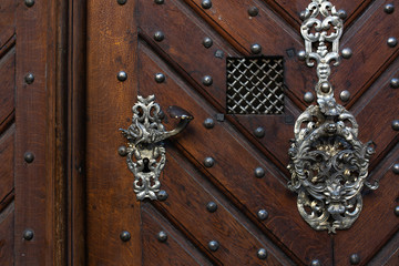 Retro metal door handle of a brown wooden door. Empty space