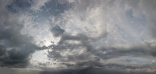 Panorama Of Cloudy Sky. Dramatic Atmosphere Preceding The Storm. Threatening Sky With Dark Clouds. Sun Rays Through Dark Clouds Of Stormy Sky