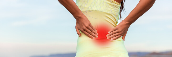 Fitness sport woman touching lower back in pain banner panorama header crop. Closeup of hands pressing on red area showing painful muscles.