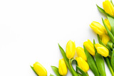 Fototapeta Kwiaty - Spring composition. Delicate yellow tulips on white background top view copy space border