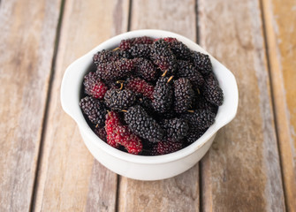 Wall Mural - The mulberry fruit in white bowl on wood table.