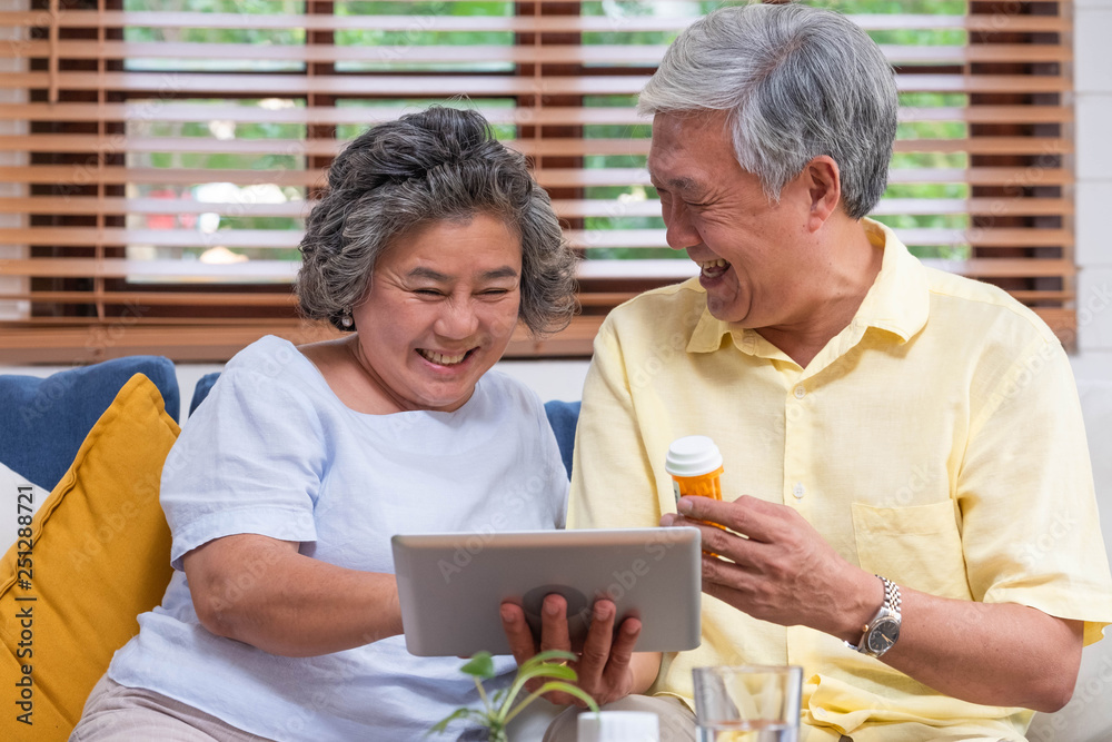 Asian senior couple use tablet video conference with doctor about pill  while sitting on sofa at home,senior learn to use technology.aging at home - obrazy, fototapety, plakaty 