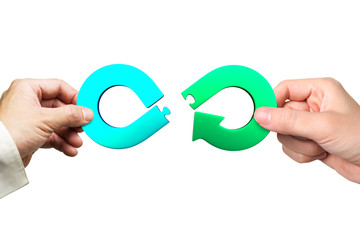 Wall Mural - Circular economy concept. Male and female hands assembling arrow infinity recycling symbol of jigsaw puzzle pieces, isolated on white background.