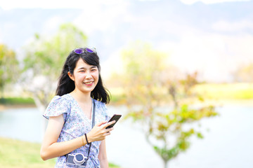 Beautiful Asian woman in blue dress holding smartphone