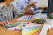 © MIND AND I - Graphic design with color swatches and tablet on a desk. Graphic designer drawing something on tablet at the office with work tools and accessories.