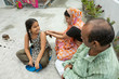 © IndiaPix - Portrait of happy Indian family sitting on a camp bed having fun