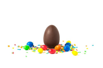 Wall Mural - Whole Chocolate Easter Egg and multicolored sweets on a white background. Easter celebration concept