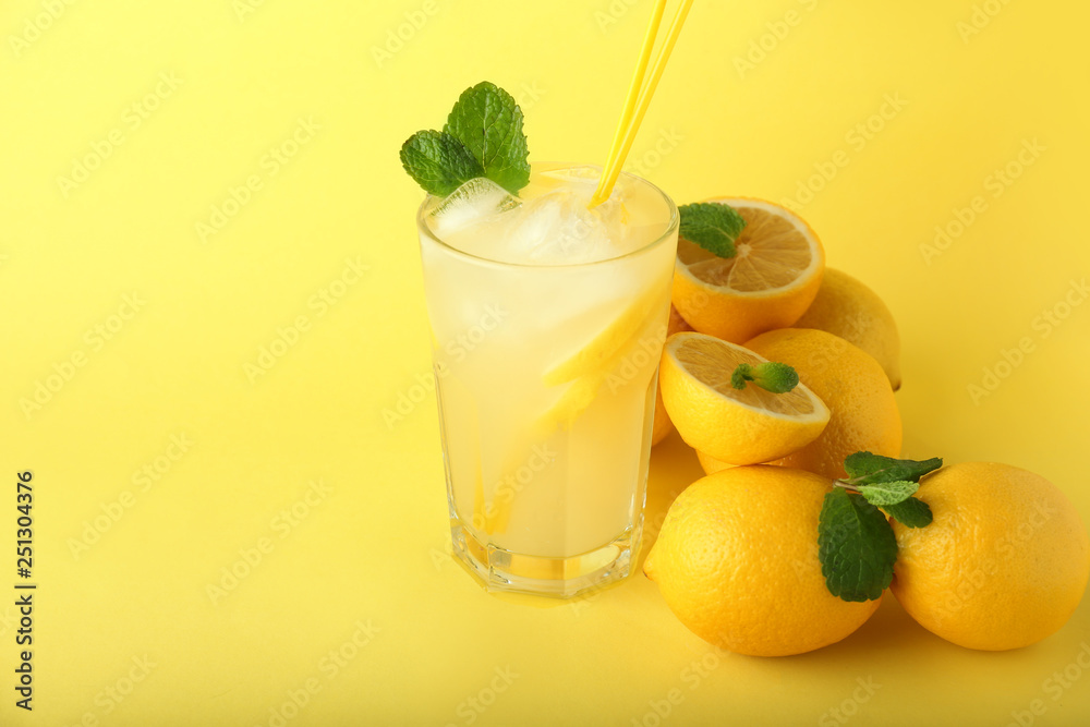 Glass of tasty cold lemonade on color background