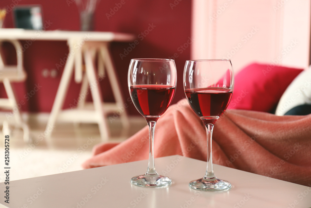 Glasses of wine on light table in living room