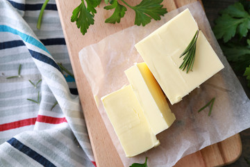 Wooden board with tasty butter and herbs on table