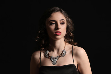 Young woman with beautiful jewelry on dark background