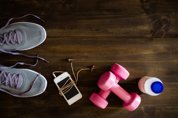 Poster - Fitness, healthy and active lifestyles Concept, dumbbells, running shoes, bottle of milk, smartphone with earphone on wooden background. Top view with copy space for text.