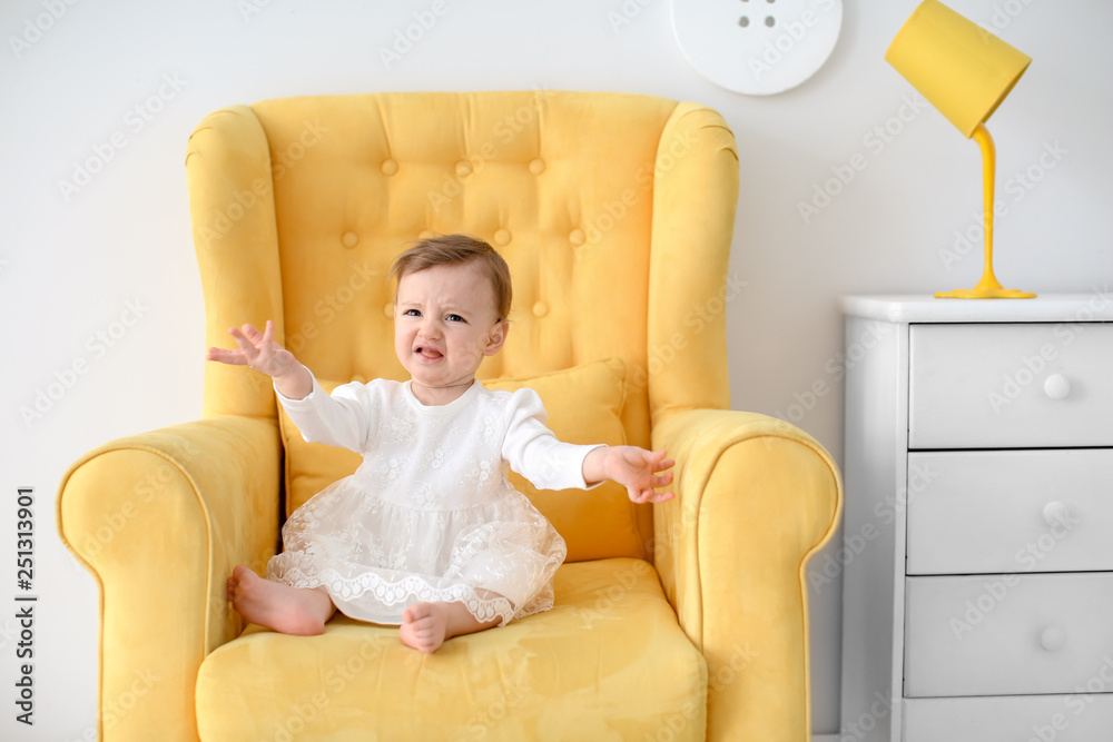 Crying little baby sitting in armchair