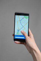 Wall Mural - Woman holding mobile phone displaying map with route on screen against grey background