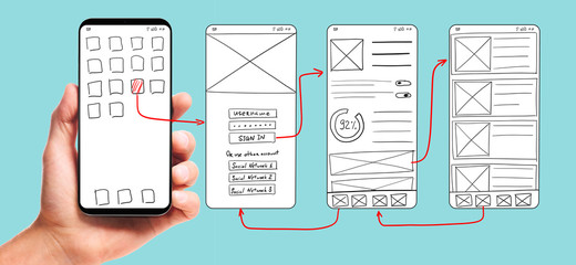 UI development. Male hand holding smartphone with wireframed user interface screen prototypes of a mobile application on blue background.