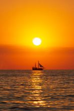 Seascape With A Sailboat On The Background Of The Setting Sun