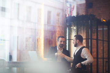 Wall Mural - Portrait of two successful business people shaking hands after meeting shot from behind glass, copy space