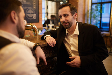 portrait of two business people chatting in cafe while sitting by bar counter