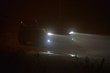 Car driving in dense fog at night.