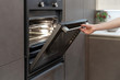 Woman opening oven with light built-in in kitchen cabinet