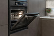 Open door on new built-in oven in black kitchen cabinet