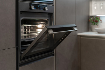 Poster - open door on new built-in oven in black kitchen cabinet