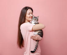 Young Attractive Woman Hugging Cat In Hands, Pink Background