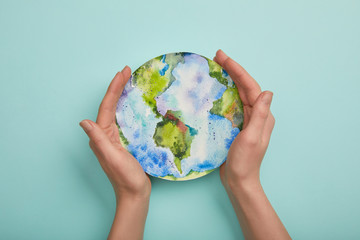 top view of woman holding planet picture on turquoise background, earth day concept