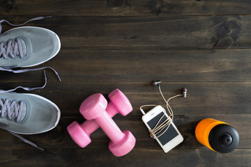 Canvas Print - Fitness, healthy and active lifestyles Concept, dumbbells, running shoes, bottle of water, smartphone with earphone on wooden background. Top view with copy space for text.