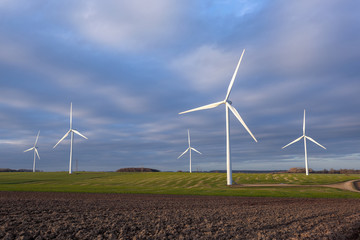 Wind turbines wind farm in field with blue sky clouds