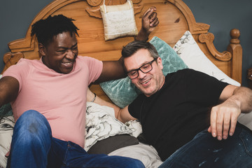 Wall Mural - An interracial gay couple pose before the camera to have their pictures taken - black man and mixed race man with stubble - on a black background - with copy space.