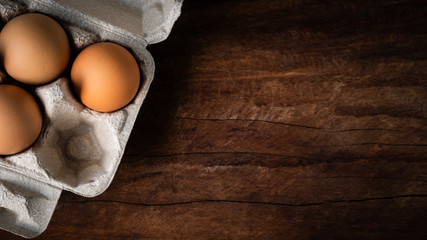 Fresh brown eggs in a carton box was placed on a wooden table to prepare food. Have copyspace to enter text. In aspect ratio 16: 9. Useful for health and easy to find according to the supermarket.