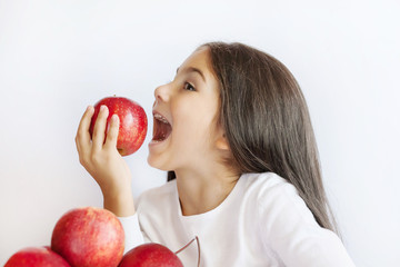 Happy cute child girl eating fresh apples. Vitamins and healthy nutrition. Beautiful face. Healthy teeth.