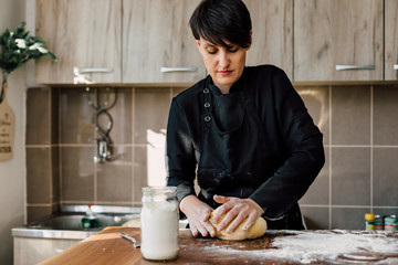 Wall Mural - Female chef kneading dough in the kitchen
