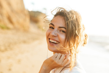 Sticker - Young woman walking outdoors at the beach looking camera.