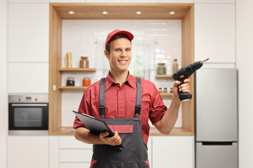 Wall Mural - Repairman holding a clipboard and a drill machine in a kitchen