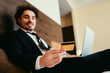 © LIGHTFIELD STUDIOS - selective focus of happy businessman shopping online with credit card and laptop in hotel room