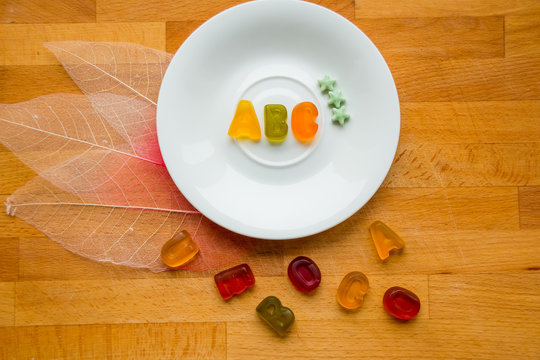ABC ,made out candy.kids candy food. Letters ABC for children alphabet. gymmy letters on white plate and on wooden board, top view