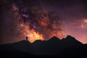Wall Mural - a beautiful starry night, a silhouette of a man, stands on a mountain and looks at the milky way gal