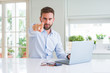 © Krakenimages.com - Handsome business man working using computer laptop pointing with finger to the camera and to you, hand sign, positive and confident gesture from the front