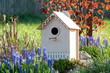 Decorative wood carved birdhouse among spring flowers