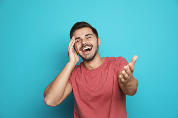 Poster - Handsome young man laughing against color background