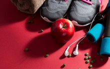 Pair Of Sport Shoes, Apple, Meetr And Towel On Red Background. Copy Space. Flat Lay – Image