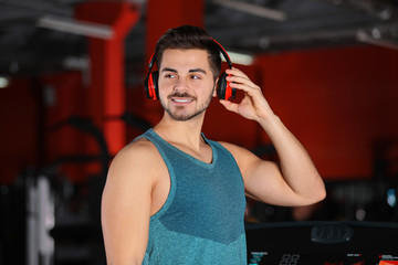 Young man listening to music with headphones at gym