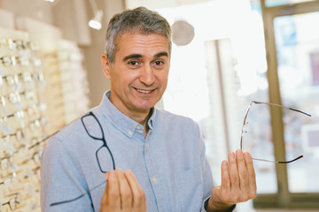 Sticker - man choosing the best glasses for him in optics store