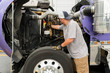 © Jamie Grill Photography/Tetra Images - Truck driver checking semi-truck engine