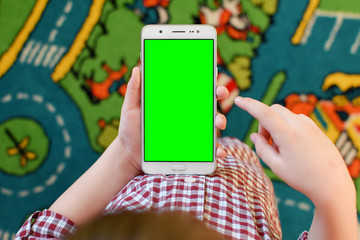 Wall Mural - A little boy holding white smartphone with green screen on colorful background