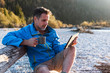 © Westend61 - Mature man camping at riverside, using tablet