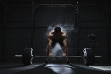 Young Crossfit Athlete Preparing Barbell For Lifting Weight At The Gym. Barbell Magnesia Protection Dust Cloud. Handsome Man Doing Functional Training. Practicing Powerlifting. Workout Exercises.